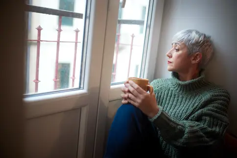 photo of woman sitting the the window